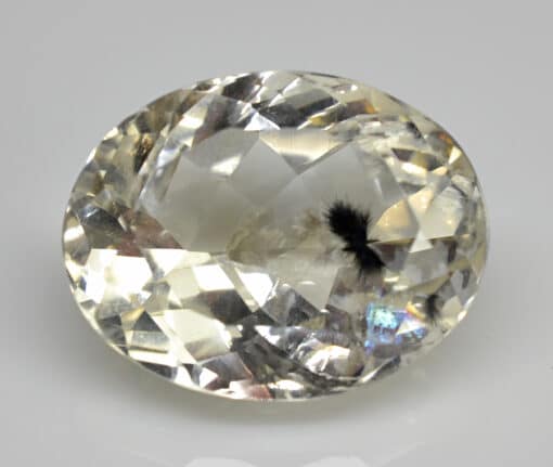 An oval cut yellow sapphire on a white surface.
