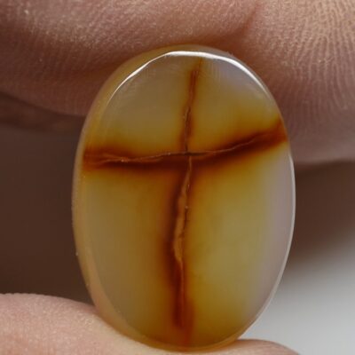 A person holding an agate stone with a cross on it.