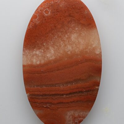 A round piece of red agate on a white surface.