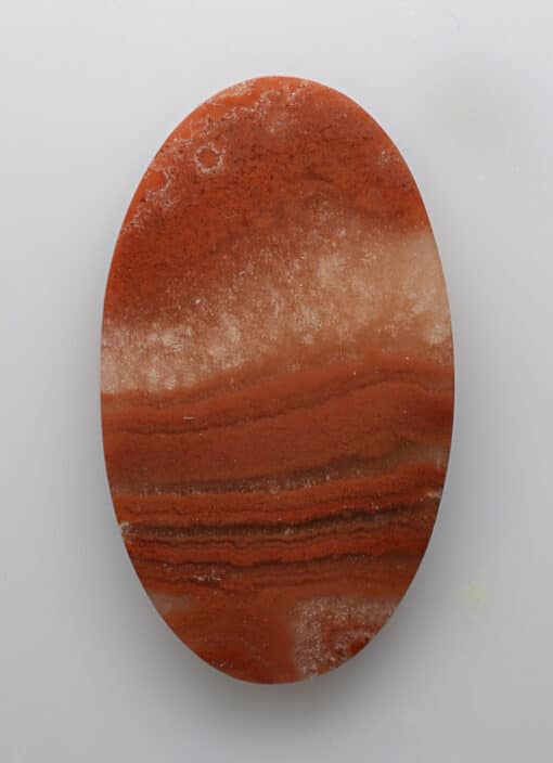 A round piece of red agate on a white surface.