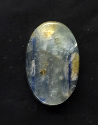 A blue and yellow cabochon on a black surface.