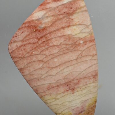 A piece of red jasper on a gray background.