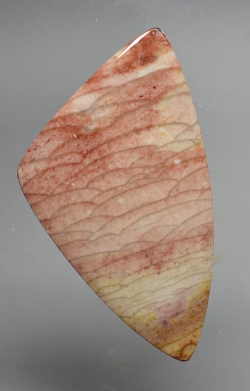 A piece of red jasper on a gray background.