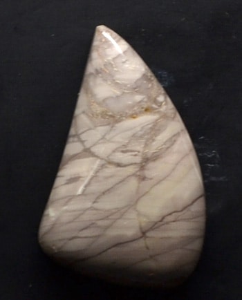 A piece of white and brown marble on a black surface.