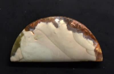 A piece of white and brown agate on a black surface.