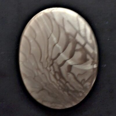 A white and brown marble pendant on a black surface.
