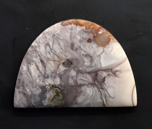 A piece of white and brown marble on a black surface.