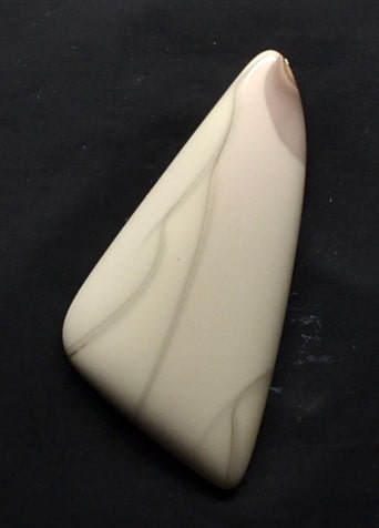 A white and brown triangle shaped pendant on a black surface.