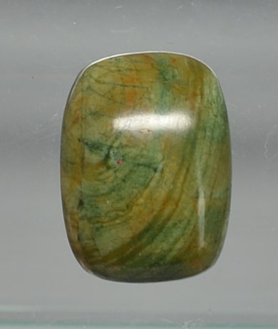 A green jade cabochon on a glass display.