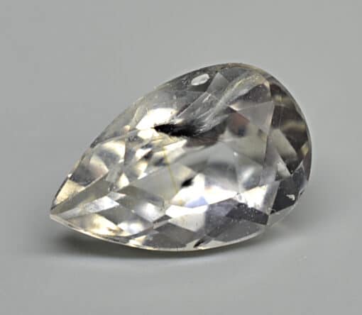 A pear shaped white sapphire on a white surface.