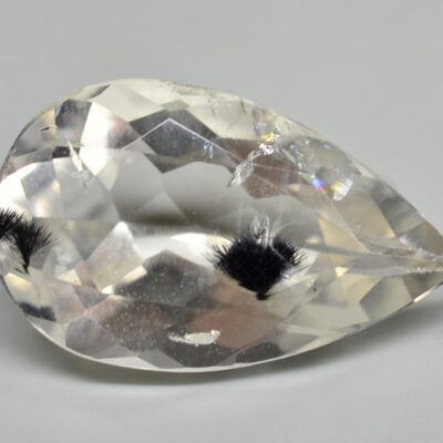 A pear shaped white topaz on a white surface.