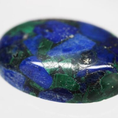 An oval lapis stone on a white surface.
