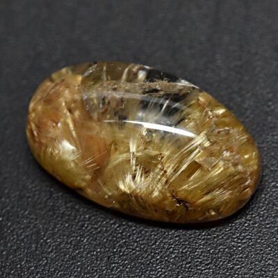 An oval shaped yellow diamond on a black surface.