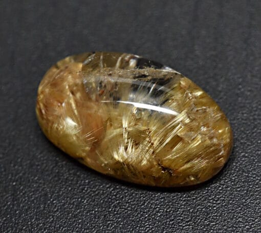 An oval shaped yellow diamond on a black surface.