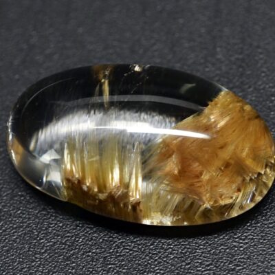 A piece of yellow quartz on a black surface.