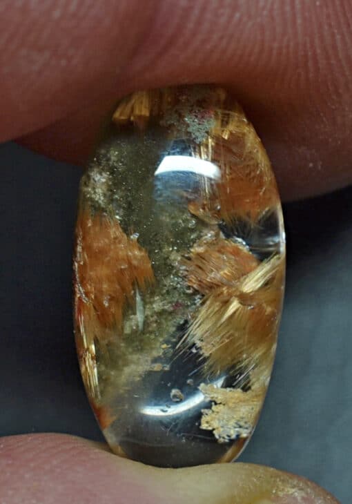 A person holding a piece of quartz with a piece of sand on it.