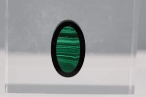 A green malachite stone in a clear glass display.