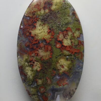 An oval shaped stone with red and green paint on it.