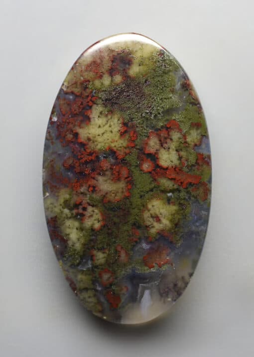 An oval shaped stone with red and green paint on it.