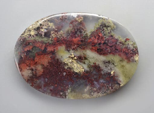 A round piece of agate with red, green, and gold.