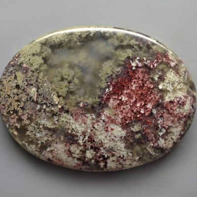 A round piece of stone with red and white specks on it.