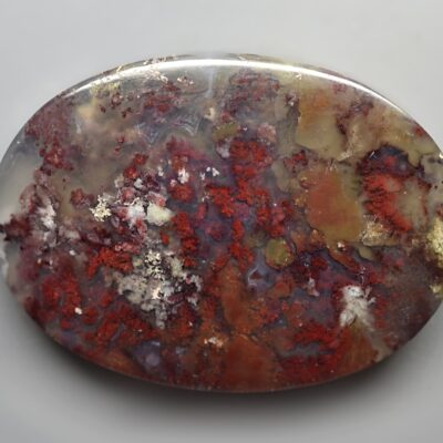A piece of red and brown agate on a white surface.