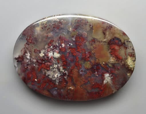 A piece of red and brown agate on a white surface.