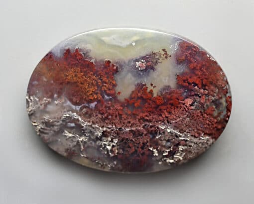 A round piece of agate with red and white swirls.
