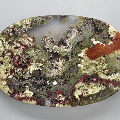 A piece of green, red, and yellow smoky quartz on a white surface.