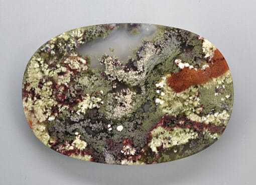 A piece of green, red, and yellow smoky quartz on a white surface.