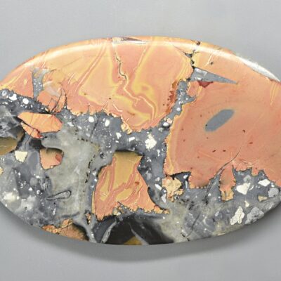 A round piece of orange and grey marble on a grey surface.
