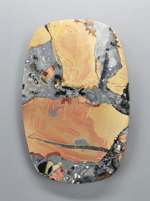 A piece of yellow, orange, and black marble on a white surface.