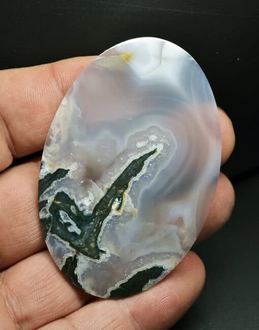 A black and white agate oval in a person's hand.