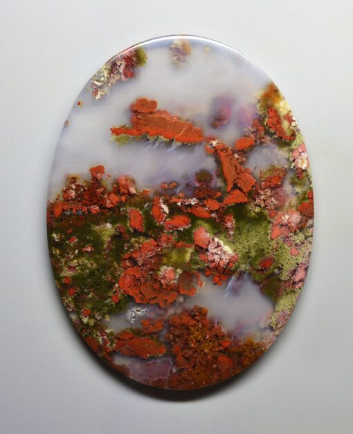 A piece of red and green agate on a white surface.