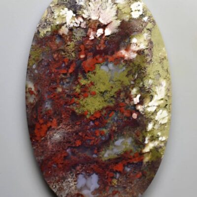 An oval piece of red, green and yellow agate.