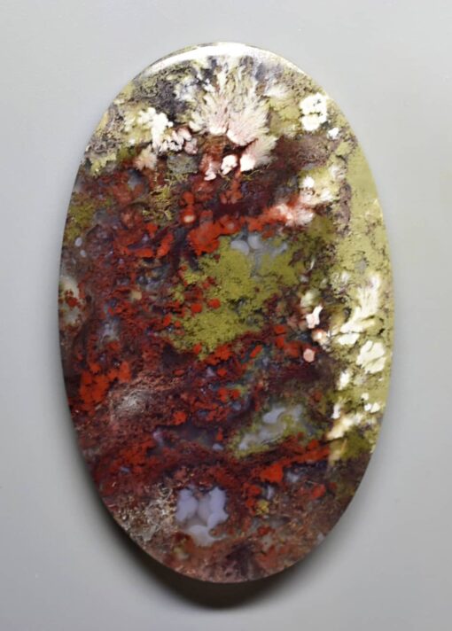 An oval piece of red, green and yellow agate.