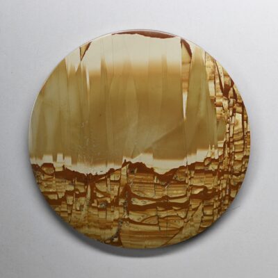 A round piece of agate with a brown and yellow pattern.