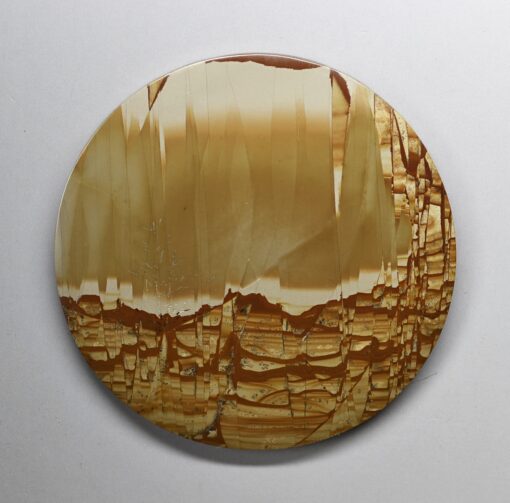 A round piece of agate with a brown and yellow pattern.