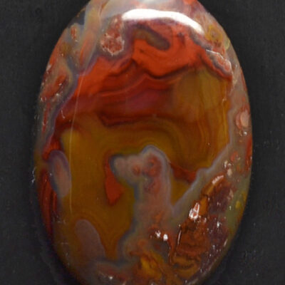 A red, orange and yellow cabochon on a black surface.