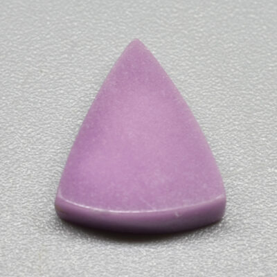 A purple triangle shaped stone on a grey surface.