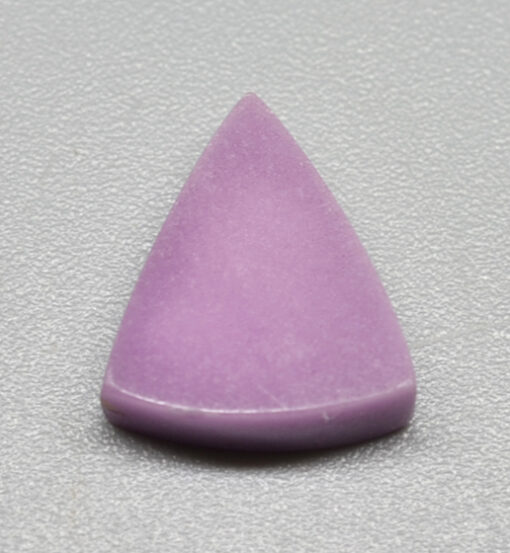 A purple triangle shaped stone on a grey surface.