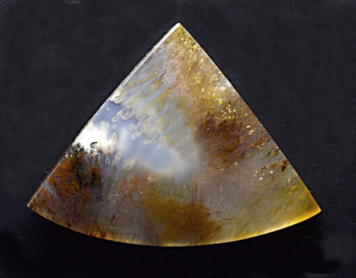 A triangular piece of agate on a Black surface.