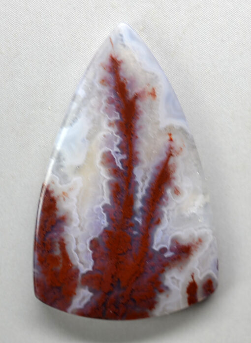 A red and white agate pendant on a white surface.