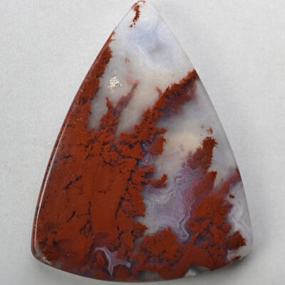 A red and white agate triangle on a white surface.