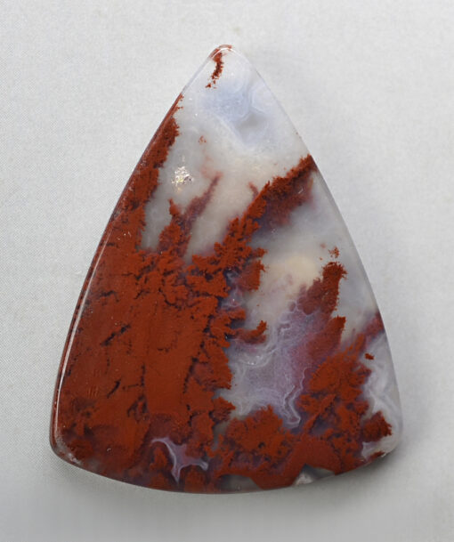A red and white agate triangle on a white surface.