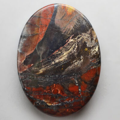 A piece of red and black jasper on a white surface.