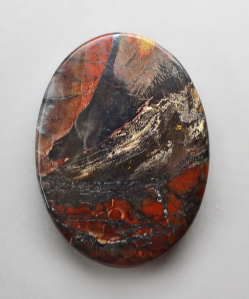 A piece of red and black jasper on a white surface.