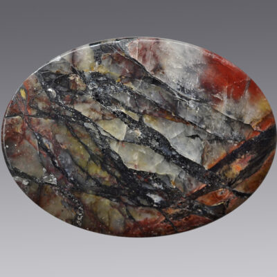 A circular piece of marble with a black and red pattern.