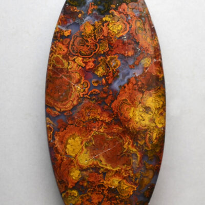 An oval shaped piece of red, orange and yellow apatite.