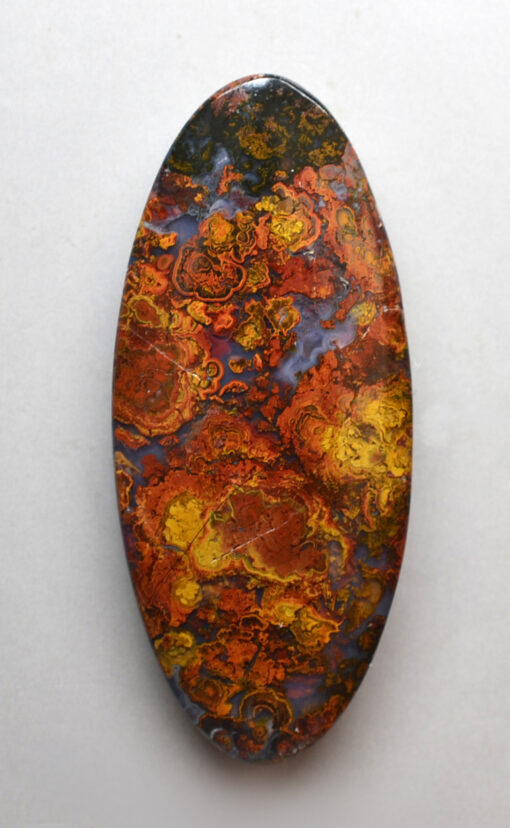 An oval shaped piece of red, orange and yellow apatite.